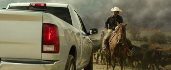 Movie still from “Hell or High Water” (2016), directed by David Mackenzie – A man riding a horse in front of a truck; Wide shot, Low angle