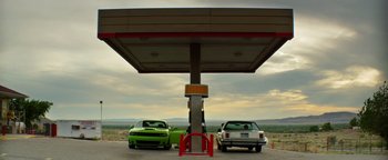 Movie still from “Hell or High Water” (2016), directed by David Mackenzie – Two cars parked at a gas station under a canopy; Extreme Wide shot, Low angle