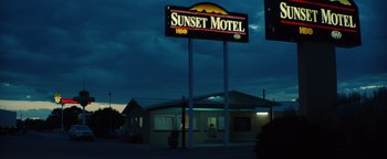 Movie still from “Hell or High Water” (2016), directed by David Mackenzie – A motel sign lit up at night with a sky background; Extreme Wide shot, Low angle