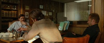 Movie still from “Hell or High Water” (2016), directed by David Mackenzie – A man sitting at a table with papers in front of him; Medium shot, Over the shoulder angle