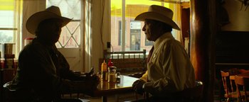 Movie still from “Hell or High Water” (2016), directed by David Mackenzie – A man sitting at a table in front of an open window; Medium shot, Over the shoulder angle