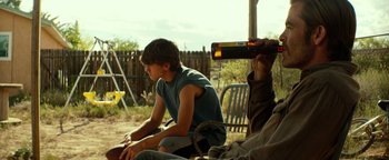 Movie still from “Hell or High Water” (2016), directed by David Mackenzie – A young man sitting on a chair next to another man; Medium shot, Over the shoulder angle