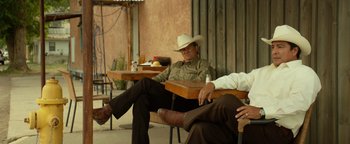 Movie still from “Hell or High Water” (2016), directed by David Mackenzie – A man in a cowboy hat sitting next to another man; Medium shot, Low angle