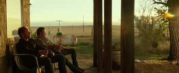 Movie still from “Hell or High Water” (2016), directed by David Mackenzie – A man sitting on a chair next to an empty gas tank; Wide shot, Over the shoulder angle