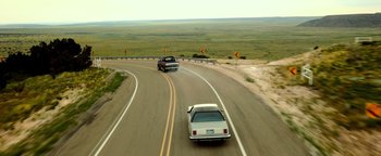 Movie still from “Hell or High Water” (2016), directed by David Mackenzie – A couple of cars driving down a curvy road; Extreme Wide shot, High angle
