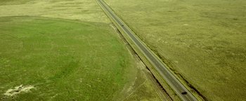 Movie still from “Hell or High Water” (2016), directed by David Mackenzie – An aerial view of an empty road in the middle of a field; Extreme Wide shot, High angle