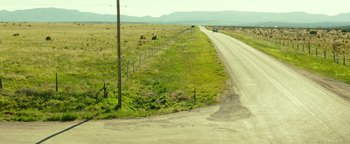 Movie still from “Hell or High Water” (2016), directed by David Mackenzie – A car is driving down a road near a field; Extreme Wide shot, High angle