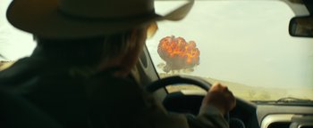 Movie still from “Hell or High Water” (2016), directed by David Mackenzie – A man driving a car in front of an explosion in the sky; Wide shot, Over the shoulder angle