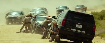Movie still from “Hell or High Water” (2016), directed by David Mackenzie – A group of men standing next to a parked car; Wide shot, Low angle