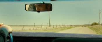 Movie still from “Hell or High Water” (2016), directed by David Mackenzie – A man's reflection in the rear view mirror of a car; Close Up shot, Over the shoulder angle