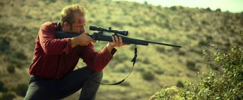 Movie still from “Hell or High Water” (2016), directed by David Mackenzie – A man is holding a rifle and aiming with a scope; Medium shot, Over the shoulder angle