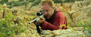 Movie still from “Hell or High Water” (2016), directed by David Mackenzie – A man with a rifle in a rocky area; Medium shot, Low angle