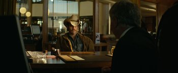 Movie still from “Hell or High Water” (2016), directed by David Mackenzie – A man wearing a cowboy hat sitting at a table; Medium shot, Over the shoulder angle