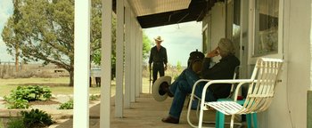 Movie still from “Hell or High Water” (2016), directed by David Mackenzie – A man in a cowboy hat is sitting on a porch; Wide shot, Over the shoulder angle