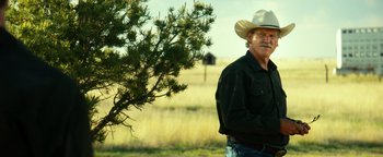Movie still from “Hell or High Water” (2016), directed by David Mackenzie – A man in a cowboy hat standing next to a tree in a field; Medium shot, Over the shoulder angle