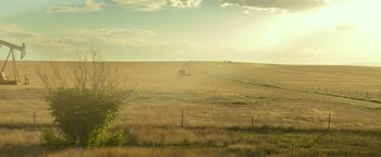 Movie still from “Hell or High Water” (2016), directed by David Mackenzie – An image of an open field with a tractor in the distance; Extreme Wide shot, High angle