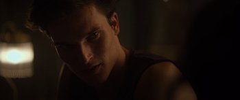 Movie still from “Hellraiser” (2022), directed by David Bruckner – A young man's face in the dark; Close Up shot, Over the shoulder angle