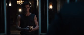 Movie still from “Hellraiser” (2022), directed by David Bruckner – A young man holding a box in a dark room; Medium shot, Over the shoulder angle