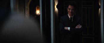 Movie still from “Hellraiser” (2022), directed by David Bruckner – A man in a suit and tie standing next to a mirror; Medium shot, Over the shoulder angle