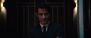 Movie still from “Hellraiser” (2022), directed by David Bruckner – A man wearing a suit and tie with his arms crossed; Close Up shot, Over the shoulder angle