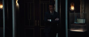 Movie still from “Hellraiser” (2022), directed by David Bruckner – A man in a suit and tie standing in front of a door; Medium shot, Over the shoulder angle