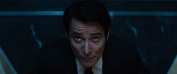 Movie still from “Hellraiser” (2022), directed by David Bruckner – A person wearing a suit and tie; Close Up shot, High angle