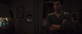 Movie still from “Hellraiser” (2022), directed by David Bruckner – A man standing with his arms crossed in a dark room; Medium shot, Over the shoulder angle