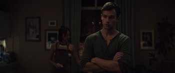 Movie still from “Hellraiser” (2022), directed by David Bruckner – A man standing next to a woman in a dark room; Medium shot, Over the shoulder angle