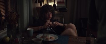 Movie still from “Hellraiser” (2022), directed by David Bruckner – A person sitting at a table with a plate of food; Medium shot, High angle