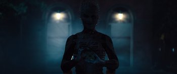 Movie still from “Hellraiser” (2022), directed by David Bruckner – A man with a face like a demon is standing in a dark room; Medium shot, Low angle