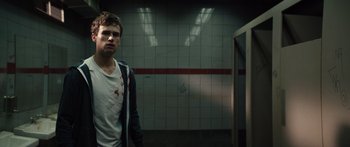 Movie still from “Hellraiser” (2022), directed by David Bruckner – A young man standing in a bathroom next to a tiled wall; Medium shot, Low angle