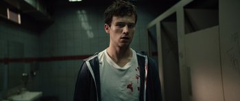 Movie still from “Hellraiser” (2022), directed by David Bruckner – A young man with blood on his shirt and hoodie; Close Up shot, High angle