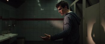 Movie still from “Hellraiser” (2022), directed by David Bruckner – A man standing in a room holding his hands out; Medium shot, Low angle