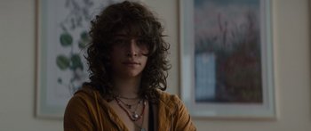 Movie still from “Hellraiser” (2022), directed by David Bruckner – A woman with long curly brown hair wearing a yellow shirt; Close Up shot, Over the shoulder angle