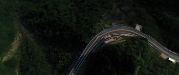 Movie still from “Hellraiser” (2022), directed by David Bruckner – An aerial view of a car driving on a curvy road; Extreme Wide shot, Overhead angle