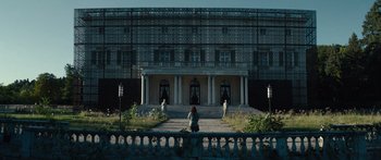 Movie still from “Hellraiser” (2022), directed by David Bruckner – A woman sitting on a bench in front of a building; Extreme Wide shot, Low angle