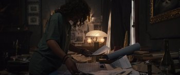 Movie still from “Hellraiser” (2022), directed by David Bruckner – A person is cutting papers at a table; Medium shot, High angle