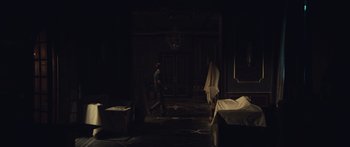 Movie still from “Hellraiser” (2022), directed by David Bruckner – A man standing in a dark room next to a bed; Wide shot, High angle