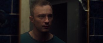 Movie still from “Hellraiser” (2022), directed by David Bruckner – A person wearing a green shirt; Close Up shot, Low angle