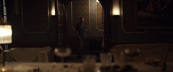 Movie still from “Hellraiser” (2022), directed by David Bruckner – A man standing in front of a room with a wine glass on the table; Wide shot, Over the shoulder angle