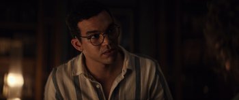 Movie still from “Hellraiser” (2022), directed by David Bruckner – A young man wearing glasses and a striped shirt; Close Up shot, Over the shoulder angle