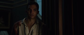 Movie still from “Hellraiser” (2022), directed by David Bruckner – A man in a striped shirt is standing in a dark room; Close Up shot, Over the shoulder angle