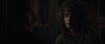 Movie still from “Hellraiser” (2022), directed by David Bruckner – A woman with curly brown hair is looking at the camera; Close Up shot, Over the shoulder angle