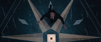 Movie still from “Hellraiser” (2022), directed by David Bruckner – A man in a suit and tie standing on a floor; Wide shot, Overhead angle