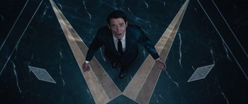 Movie still from “Hellraiser” (2022), directed by David Bruckner – A man in a suit and tie standing in front of a wall; Medium shot, Overhead angle