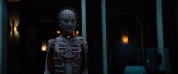 Movie still from “Hellraiser” (2022), directed by David Bruckner – A person in a costume is standing in front of a building; Close Up shot, Low angle