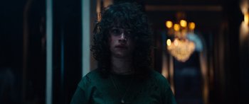 Movie still from “Hellraiser” (2022), directed by David Bruckner – A woman with curly black hair wearing a green shirt; Close Up shot, Over the shoulder angle