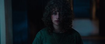 Movie still from “Hellraiser” (2022), directed by David Bruckner – A woman with curly black hair wearing a green shirt; Close Up shot, Over the shoulder angle