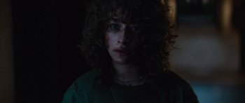 Movie still from “Hellraiser” (2022), directed by David Bruckner – A person with curly hair wearing a green shirt; Close Up shot, Low angle