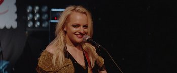 Movie still from “Her Smell” (2018), directed by Alex Ross Perry – A woman with blonde hair is holding a microphone; Close Up shot, Over the shoulder angle